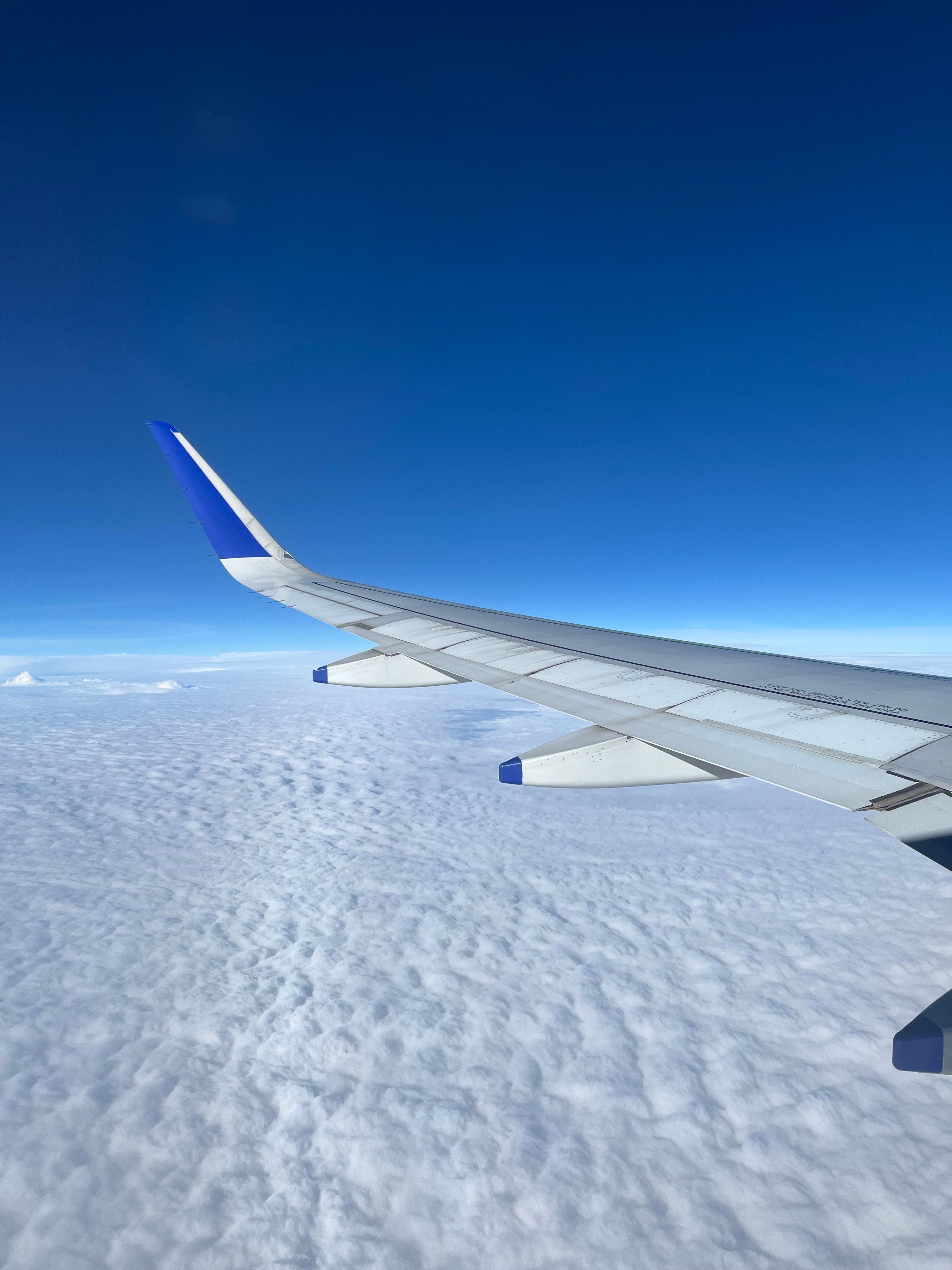 Airplane wing view above clouds representing international travel